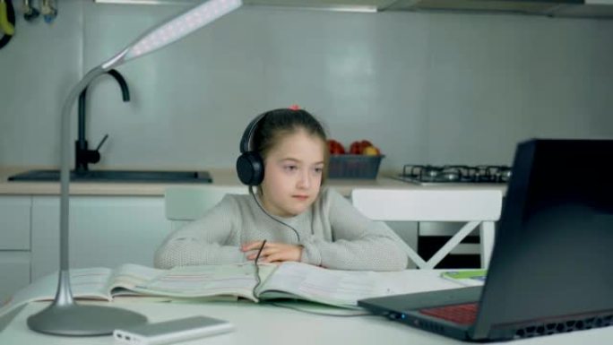 女校小学生戴着耳机在家在线学习观看网络课或通过视频通话听力辅导