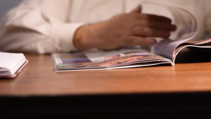 男人坐在桌子旁看杂志