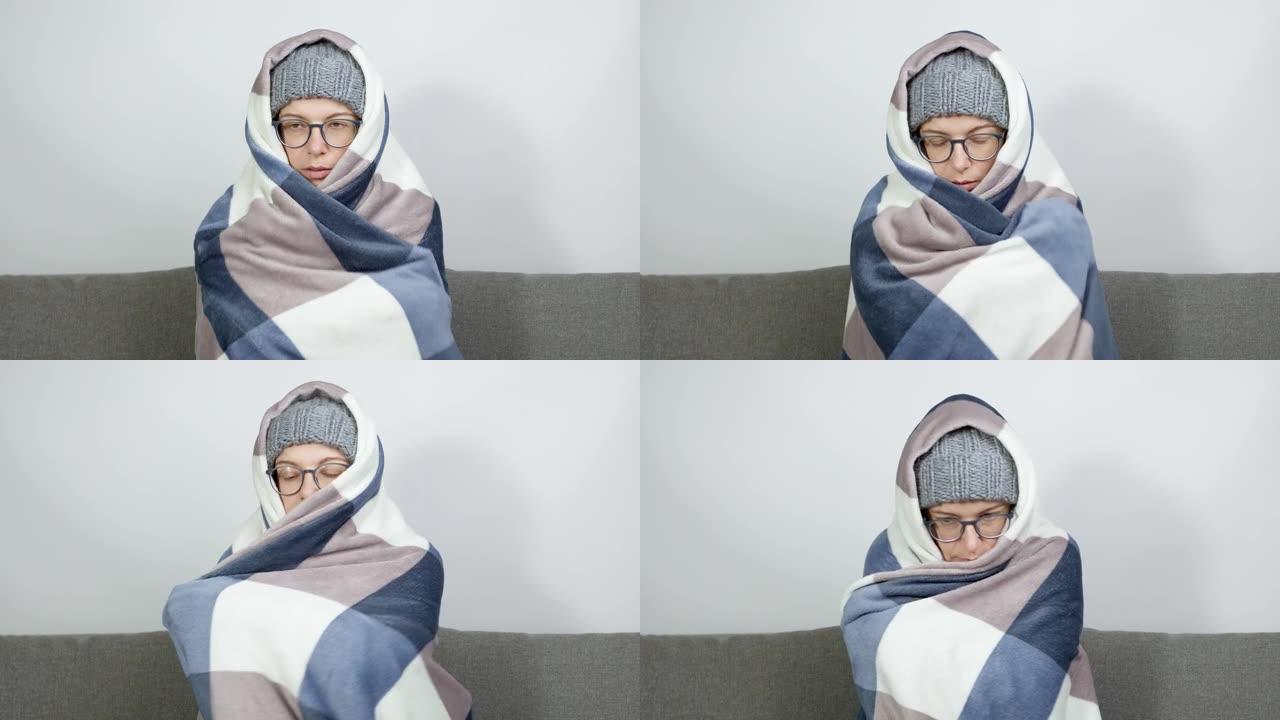 冬天，一个裹着毯子的女人坐在寒冷的房间里温暖自己。