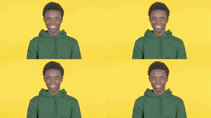 黄色背景上微笑的非洲年轻人