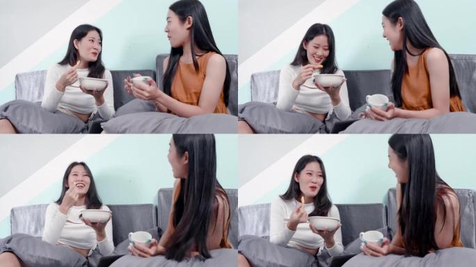 4K，周末入住后，两名亚洲美女在民宿客厅沙发上吃零食。聊得很开心，并计划在招待所四处旅行。
