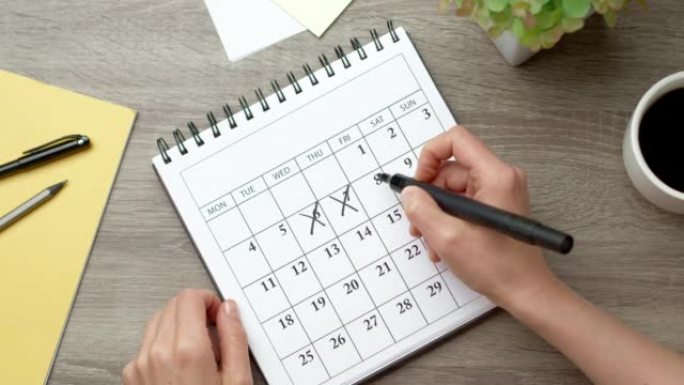 女人的手划掉日历上的日子。概念规划和截止日期。