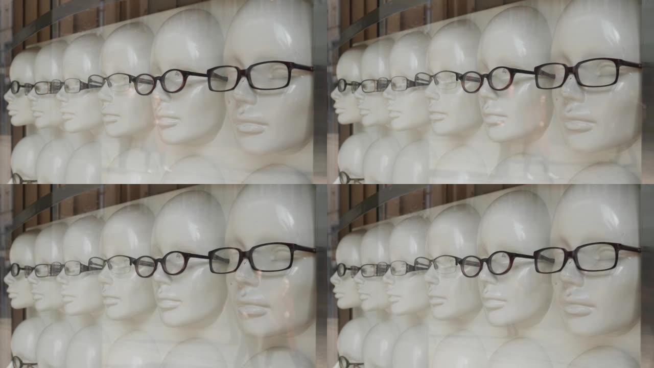 眼镜商店在白色人体模型上的展示柜在玻璃后面