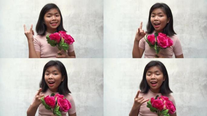 亚洲少女手持一束粉红玫瑰，摆姿势沙卡标志，决心决定成功，白色旧墙背景