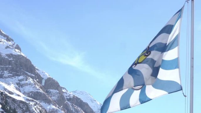 瑞士Grisons Canton旗飘扬，背景是白雪皑皑的山脉。低角度