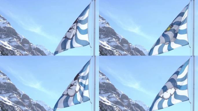 瑞士Grisons Canton旗飘扬，背景是白雪皑皑的山脉。低角度