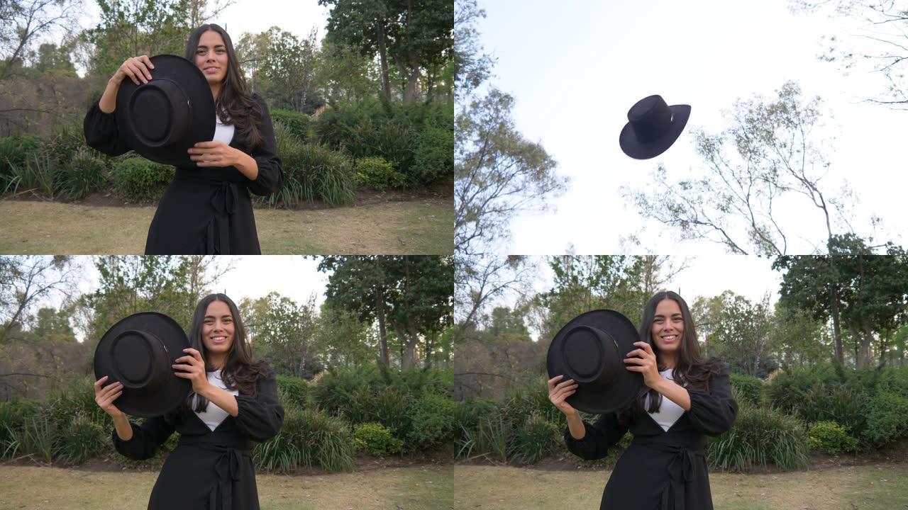 一个欢快的西班牙裔妇女在4k拍摄的公园里向空中扔软呢帽的浅浅焦点
