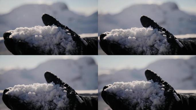冬季手套中人的手的特写在模糊的背景上高海拔上夹着许多新鲜的雪