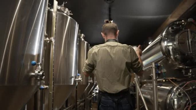 啤酒酿造商在现代啤酒厂的手中拿着金属桶