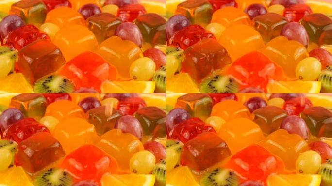 在带有葡萄，橙片和猕猴桃的多色浆果明胶果冻上滴滴橙汁。