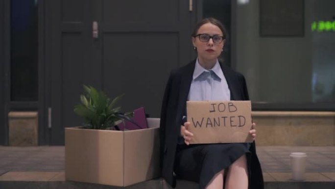 绝望的年轻女子拿出工作的纸板招牌坐在街上