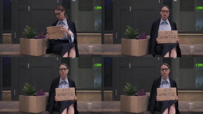 绝望的年轻女子拿出工作的纸板招牌坐在街上