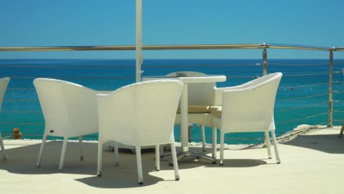 海边的咖啡馆。地中海背景下的白色雨伞下的桌椅。