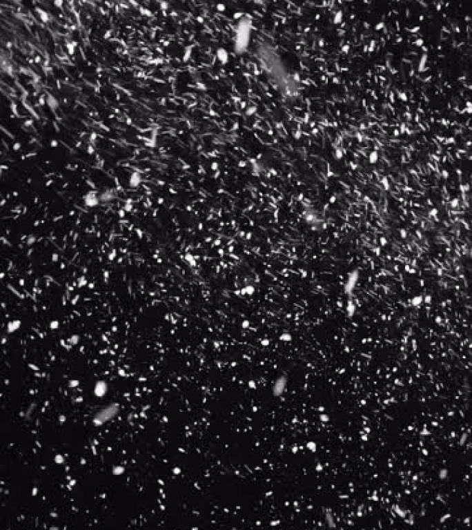 黑色背景上暴风雨中雪花落下的垂直视频。
