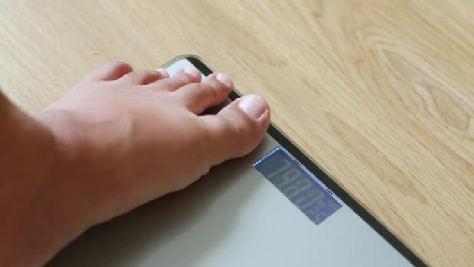 特写胖子踩在秤上测量体重