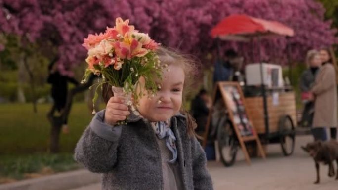公园里一个可爱的小女孩，在拥挤的小巷里，手里拿着一束鲜花。