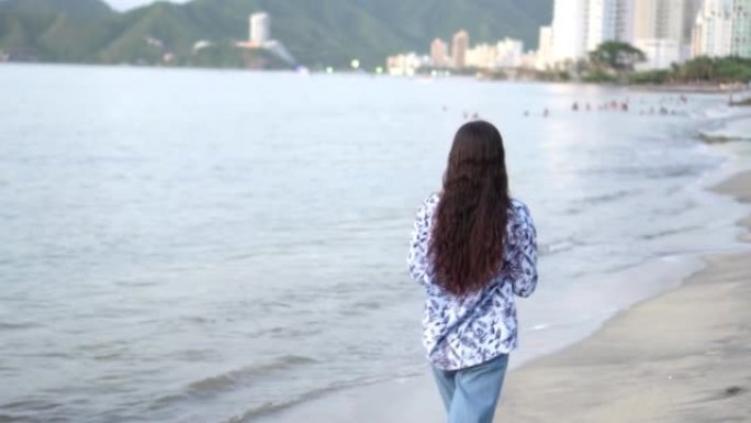 年轻女子的头发在户外漫步在海滩上