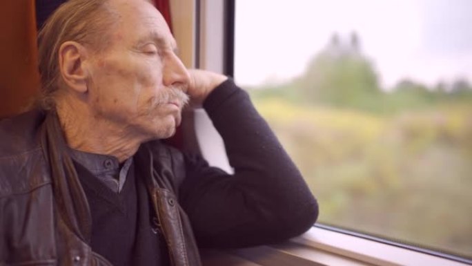戴着眼镜的老人的特写镜头在火车上旅行，看着窗外