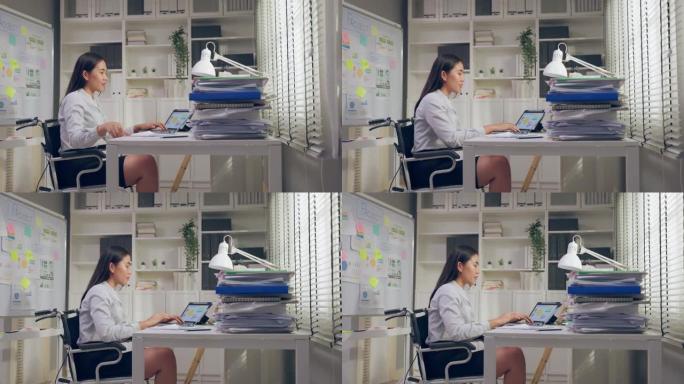 亚洲年轻的腿部截肢者女商人在办公室工作时幸福快乐。穿着正式服装的有吸引力的无腿员工坐在桌子上，并在公