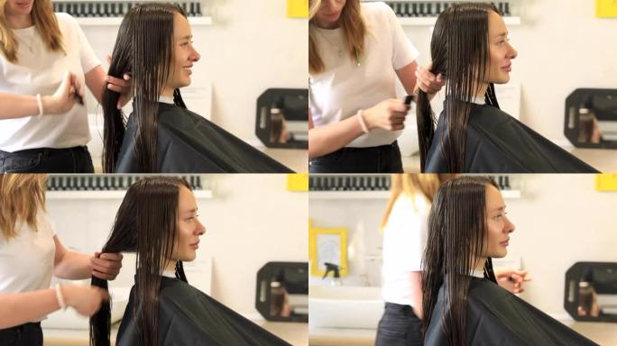 专业美发师在剪头发前用梳子梳理客户的黑色湿长发。