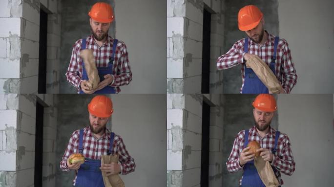 建筑工地。穿着橙色头盔的建筑工人在午餐时吃汉堡