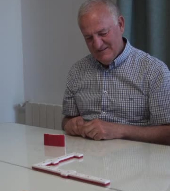 玩多米诺骨牌的老人看着镜头大笑。多米诺骨牌是一种古老的瓷砖游戏