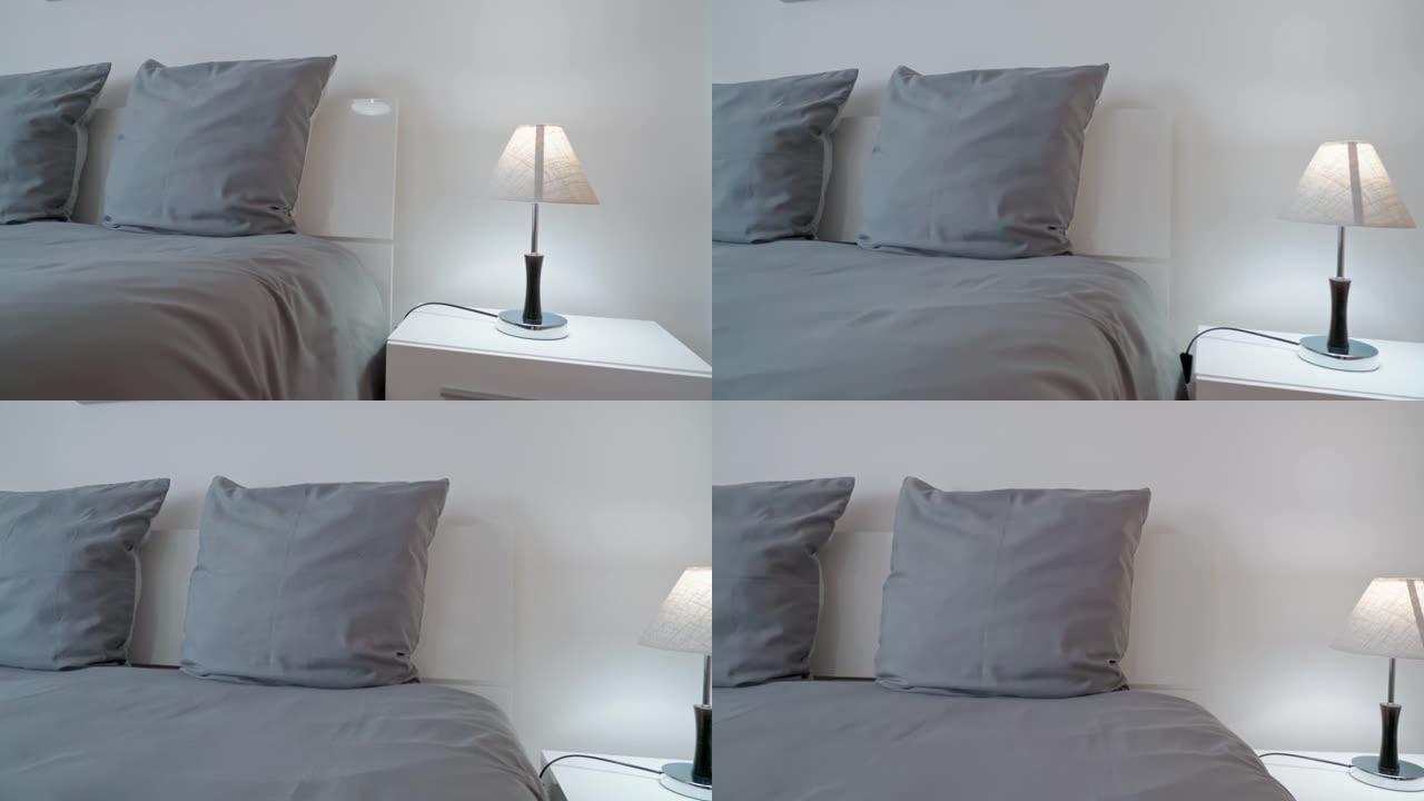 现代简约卧室，放松和睡眠。床头柜上的简约灯，用于灰色枕头。