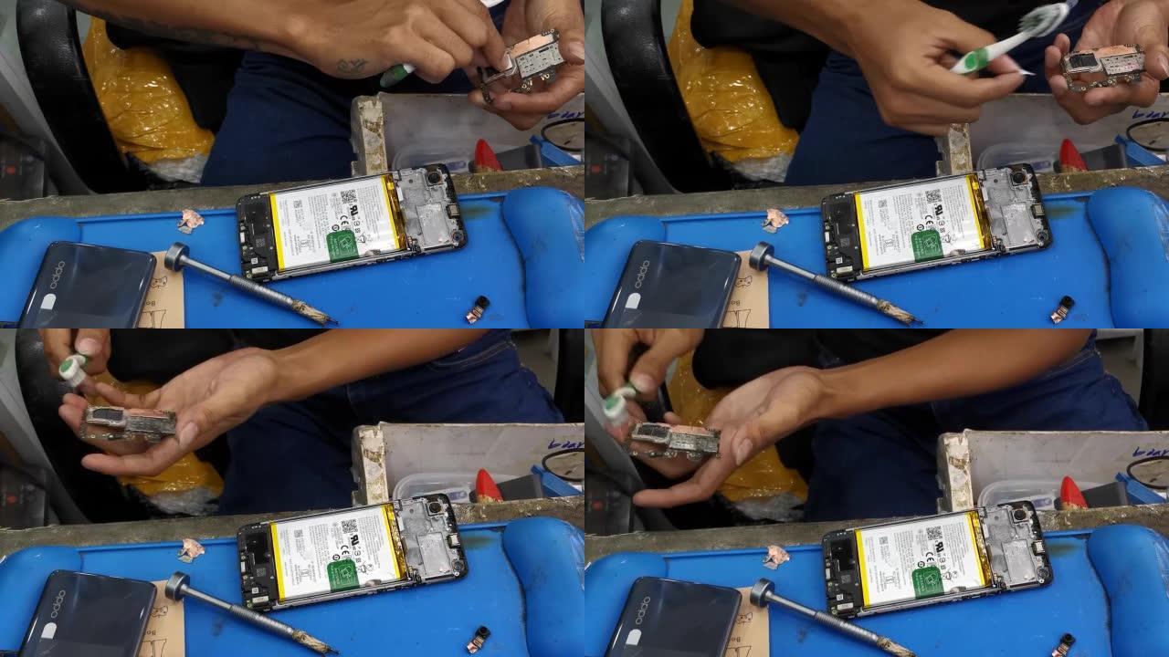 手机技术人员清洁刷手机主板进行维修。特写镜头。