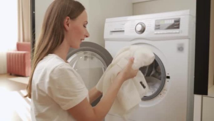 年轻女子从洗衣机里拿出干净的白色内衣。一个女人喜欢新鲜内衣的味道