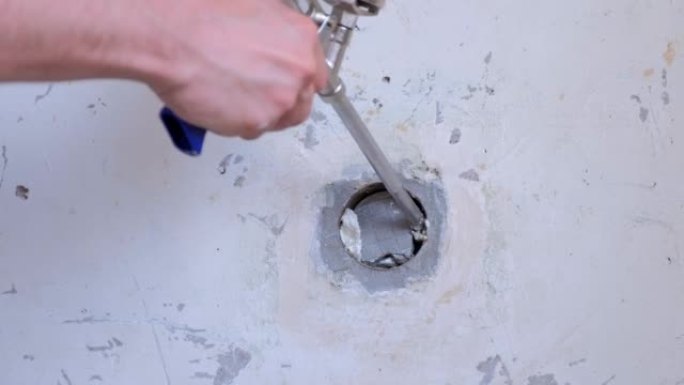 人在混凝土板安装泡沫的墙壁上填充孔，在家中进行维修。