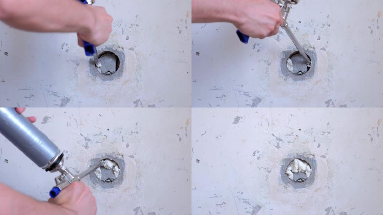 人在混凝土板安装泡沫的墙壁上填充孔，在家中进行维修。