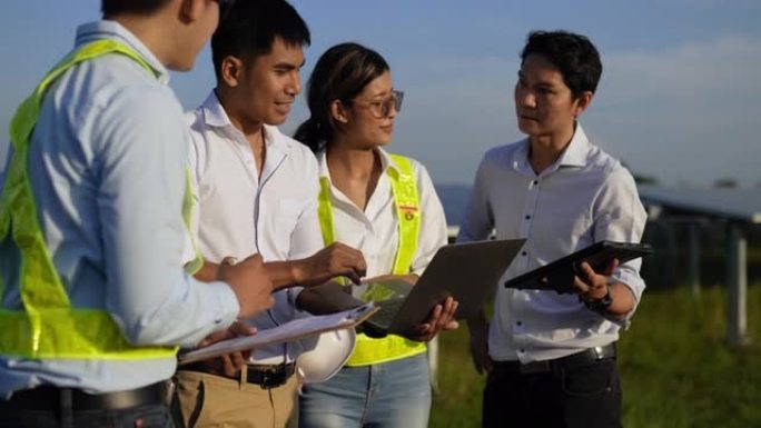 特写镜头，一组亚洲工程团队在计划操作和车站光伏太阳能电池板期间使用笔记本电脑和平板电脑，年轻的检查员