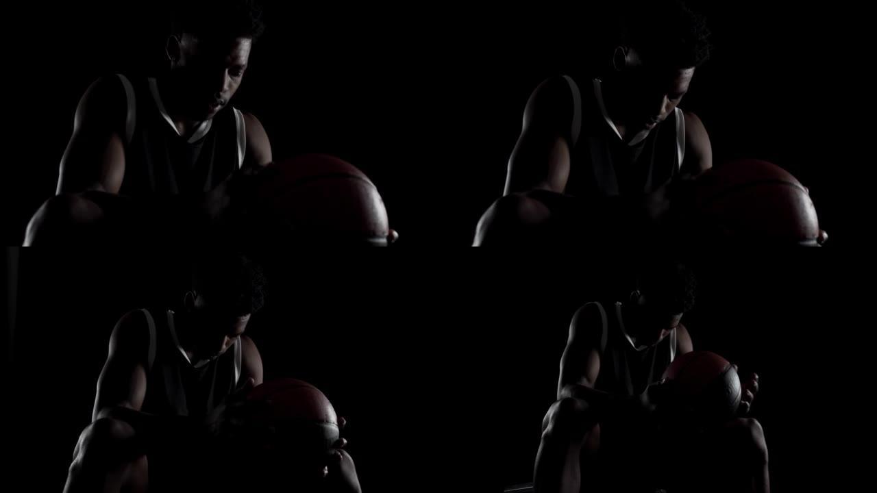 篮球运动员坐在长凳上深呼吸。黑人背景下的非裔美国体育人。