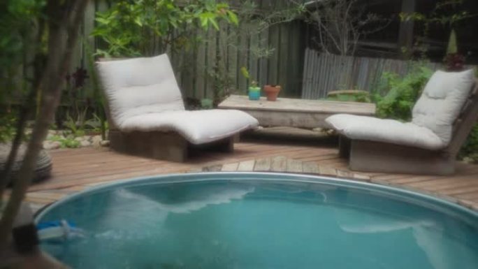 小游泳池旁边有两把带柔软白色靠垫的椅子