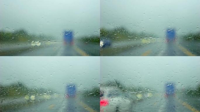 在雨中在高速公路上行驶。雨滴在挡风玻璃上的特写。雨刮器擦拭汽车雨水湿的挡风玻璃。