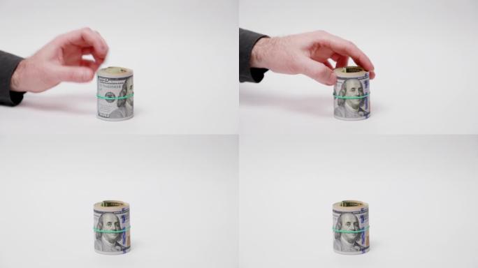 省钱。男人用卷起的美钞盖住存钱罐。白色背景上的手和现金特写。通货膨胀与投资的概念