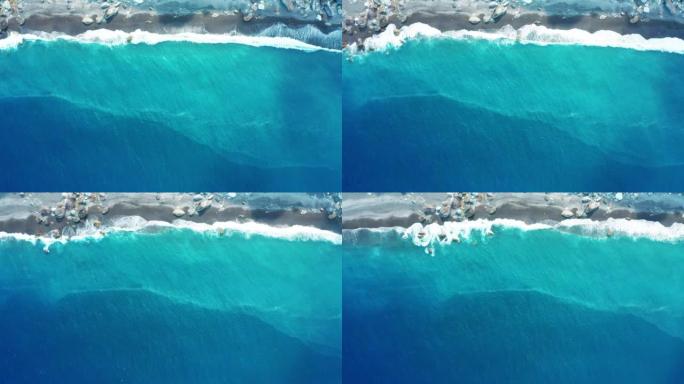 海洋蓝浪在海滩上断裂的空中俯视图。