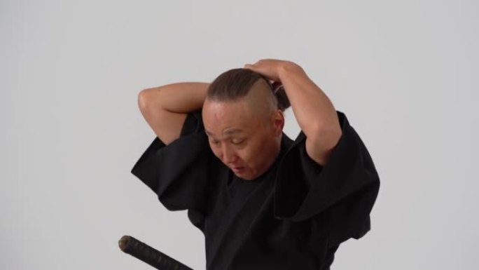 一个穿着黑色和服的日本武士把头发扎成一个发髻