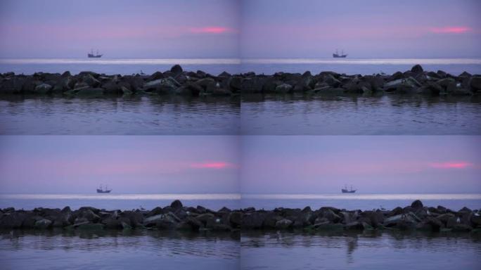 波罗的海。蓝色小时。前景石质防波堤上的海鸥。背景中风格化为海盗的船。紫色。波兰达尔沃沃