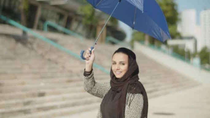戴着头巾的年轻穆斯林妇女头顶着伞。