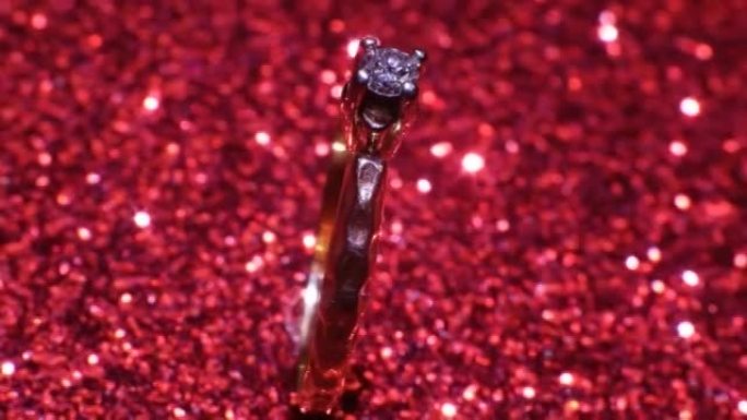 美丽闪亮的金色订婚戒指，闪闪发光的红色背景上有大宝石钻石。情人节礼物。