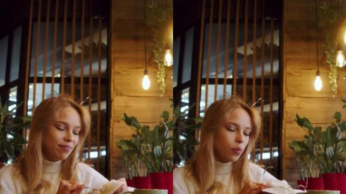 年轻女子坐在咖啡馆擦眼镜表面。垂直4k镜头。