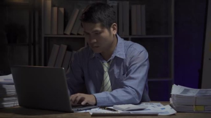 商人加班，商人在办公室深夜用台式计算机努力工作。商务人士加班。工资人的概念。