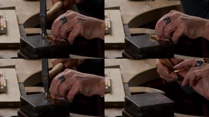 一只老年女性手的特写镜头用锤子给金锭打形状