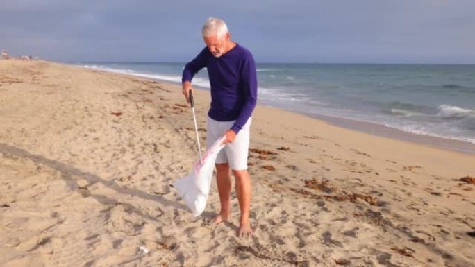 成熟的男人在海滩上捡垃圾