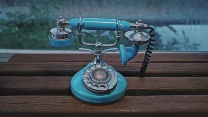 一个女人的手拿起一个老式的蓝色旋转电话听筒打电话。老式手机。