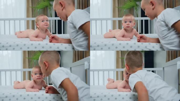 顽皮的新生儿微笑着躺在婴儿床里。哥哥和婴儿玩耍，站在家里床边爱抚他。