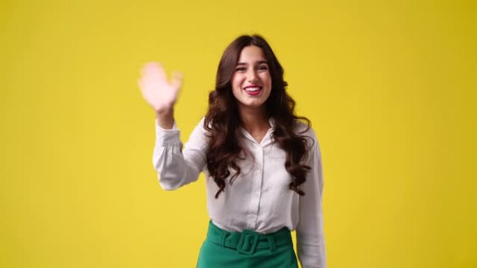 一个女孩在黄色背景上挥手打招呼的4k视频。