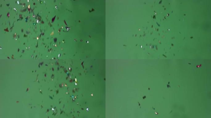 视频4k色彩丰富的派对波普尔掉落在绿屏背景上的五彩纸屑。概念庆祝节日。
