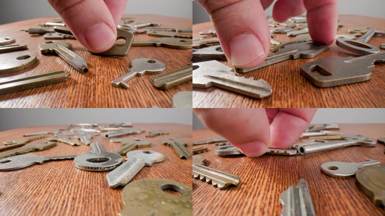 镜头在旧木制背景上的钥匙上移动。男人的手指拿着钥匙。